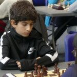 Jeune joueur en survêtement noir concentré sur sa partie lors des championnats jeunes de l'Essonne.