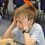 Un jeune joueur, la tête dans la main, réfléchit devant son échiquier lors des championnats de l'Essonne.