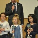 Trois jeunes joueuses tiennent leur coupe sur le podium des Championnats d'Essonne Jeunes.