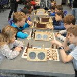 Jeunes joueurs attablés devant leurs échiquiers et leurs pendules lors des championnats jeunes de l'Essonne.