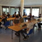 Salle de jeu vitrée avec les participants penchés sur leurs échiquiers au Grand Prix Jeunes 2021.