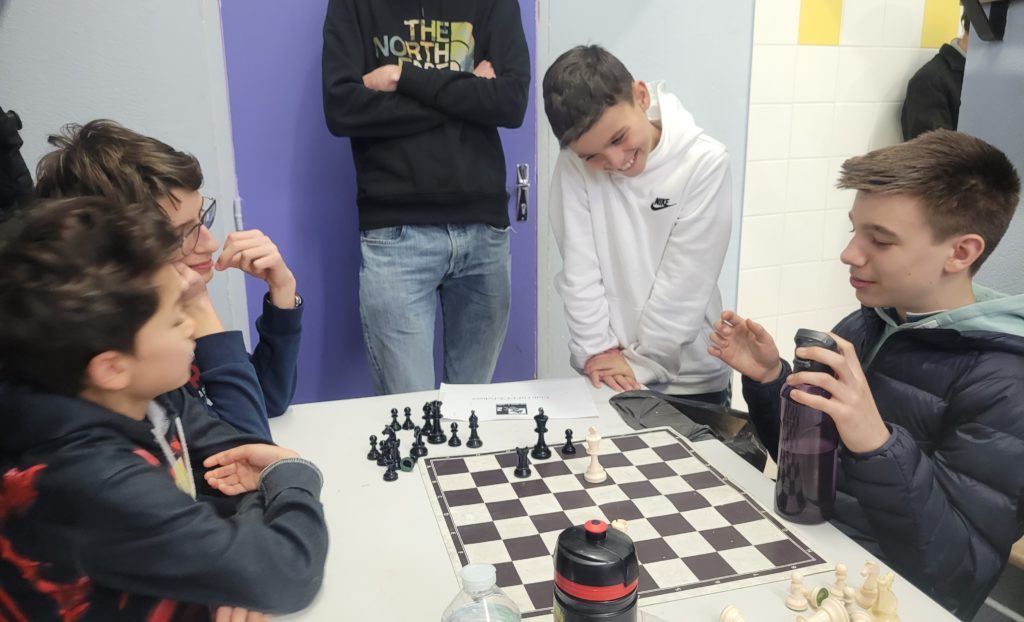 Jeunes joueurs souriants autour d'un échiquier pendant les championnats jeunes d'Île-de-France.