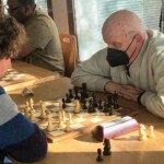 Un joueur senior masqué face à son adversaire, concentré sur la partie, lors du 22e Open de Gif.