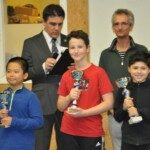 Trois jeunes joueurs brandissent leurs coupes, entourés des organisateurs, aux championnats d'Essonne 2019.