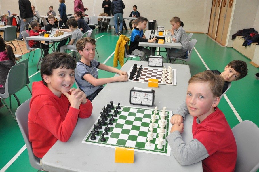 Jeunes joueurs souriants devant leurs échiquiers à l'étape de Nozay du Grand Prix de l'Essonne.