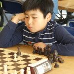 Un jeune joueur concentré, la tête posée sur la main, devant son échiquier au 20e Open de Gif.