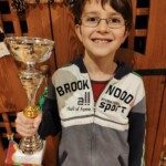 Jeune joueur souriant tenant sa coupe après le Championnat Écoles et Collèges 2019.