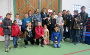 Groupe de jeunes joueurs posant avec leurs coupes dans un gymnase après le Championnat de l'Essonne Jeunes.
