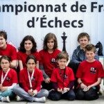 Les jeunes du club en maillot rouge posent devant le décor du Championnat de France d'échecs à Montbéliard.