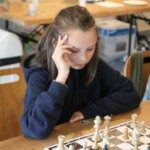 Une jeune joueuse concentrée devant son échiquier lors de la compétition interdépartementale Loiret-Essonne.