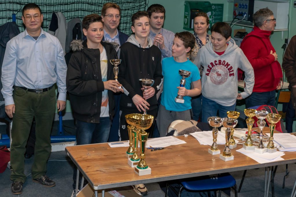 Équipe de collégiens brandissant leurs coupes devant la table des trophées au Championnat Écoles et Collèges.