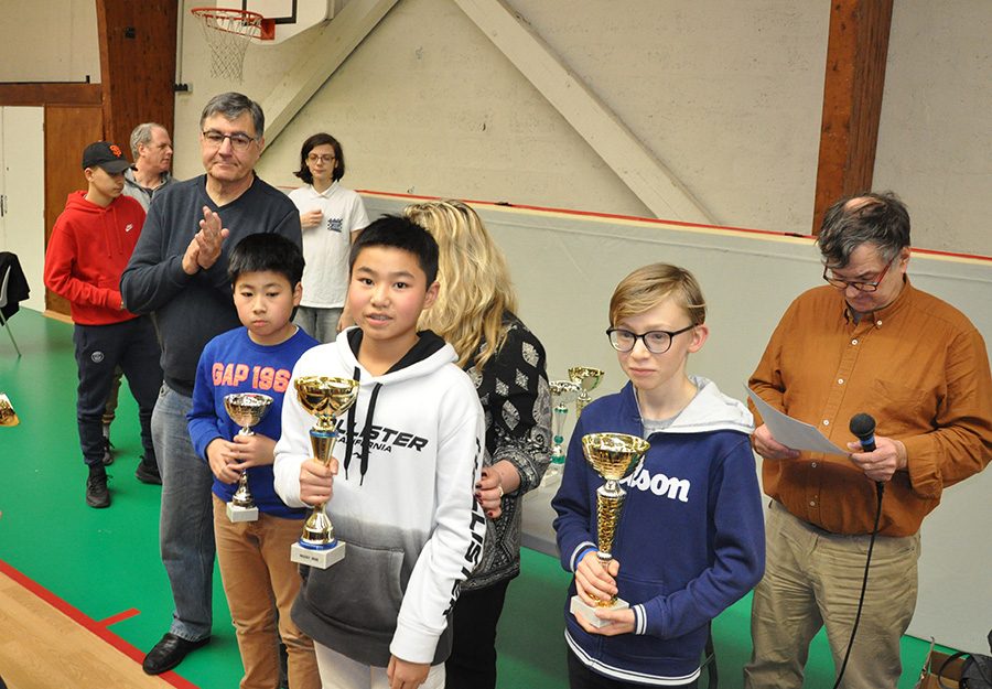 Trois jeunes joueurs reçoivent leurs coupes dans le gymnase à l'étape de Nozay du Grand Prix de l'Essonne.