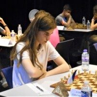Une joueuse concentrée sur sa partie, entourée d'autres échiquiers, lors du tournoi d'Avoine.