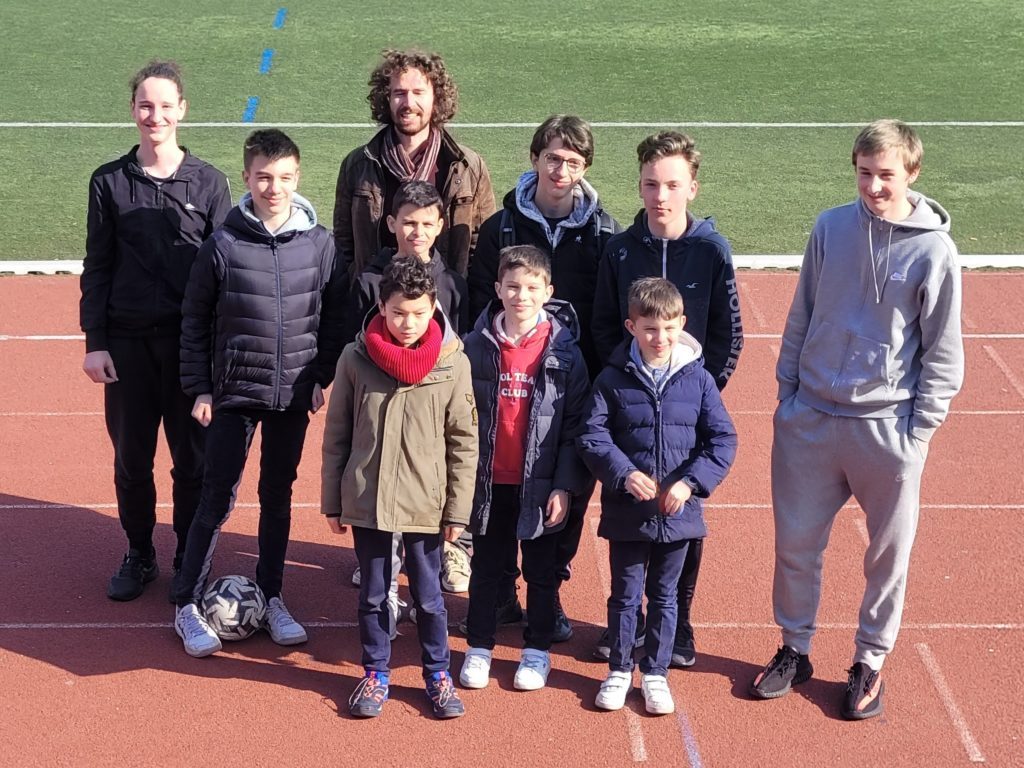 Groupe de jeunes joueurs et leur accompagnateur posant en extérieur avant les Championnats jeunes d'Île-de-France.