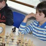 Un jeune joueur en pull rayé, concentré sur sa partie lors de l'étape de Gif du Grand Prix Jeunes.