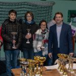 Jeunes lauréats et organisateurs posant derrière la table des coupes du Championnat Écoles et Collèges.