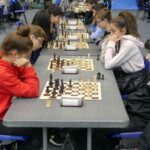 Longue rangée d'échiquiers avec de jeunes joueuses face à face aux championnats jeunes de l'Essonne.