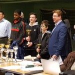 Remise des prix du Championnat Écoles et Collèges, coupes alignées devant les lauréats et officiels.