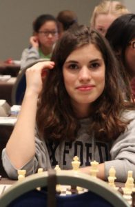 Une joueuse souriante derrière son échiquier lors des Championnats du Monde jeunes.