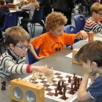 Jeunes joueurs concentrés autour de leurs échiquiers et pendules aux Championnats jeunes de l'Essonne.