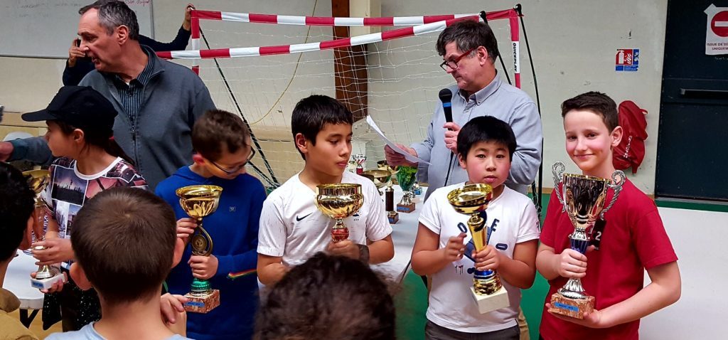 Quatre jeunes joueurs reçoivent de grandes coupes à la remise des prix de la 1re étape du Grand Prix.