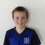 Portrait souriant d'un jeune joueur du club en maillot bleu lors du goûter de fin de saison.