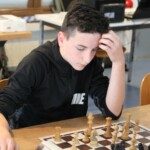Un jeune joueur en sweat noir réfléchit devant son échiquier lors de la compétition interdépartementale.